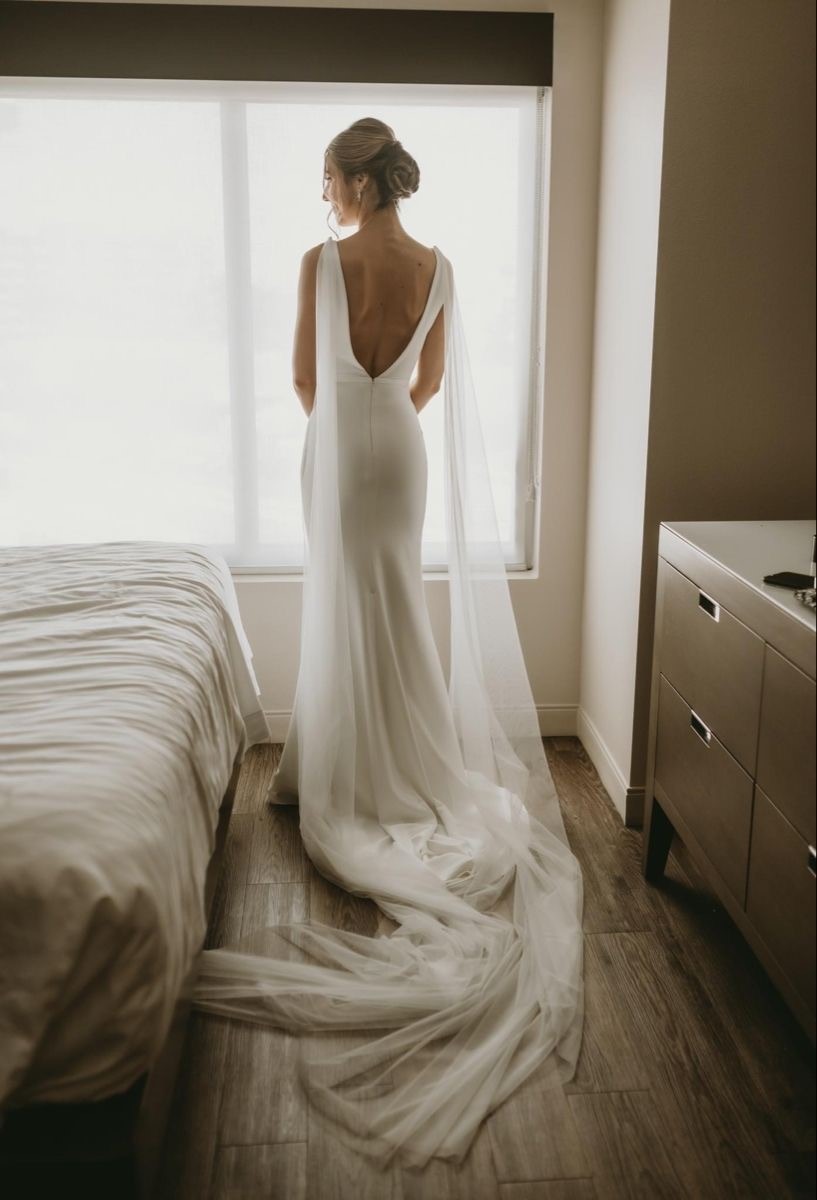 Bride in a White Gown Standing by a Window in a Hotel Room