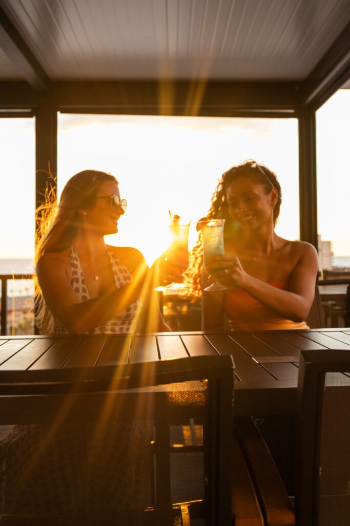 Two Women Enjoying Sunset Drinks at a Rooftop Bar